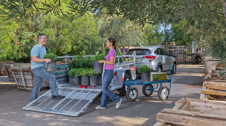 A couple loading plants into a U-Haul utility trailer