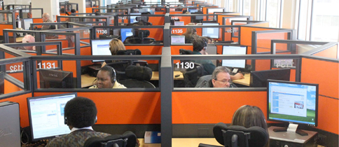 Building filled with cubicles and employees at a computer.