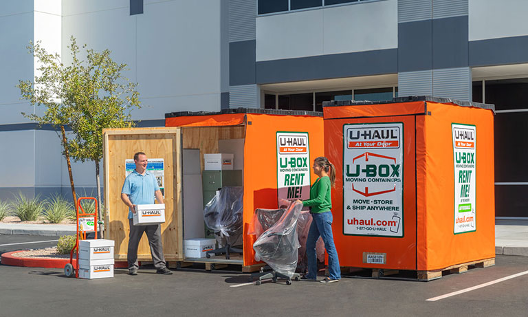 A couple loading 2 UBox containers with boxes and office furniture