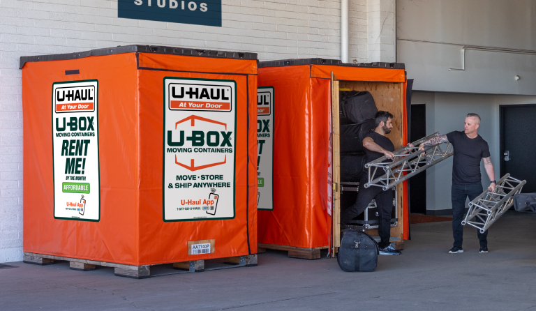 2 construction managers reviewing blueprints in front of a UBox container
