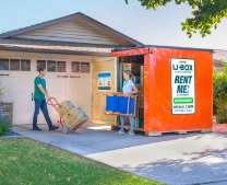 A couple unloading a UBox container in the driveway of a residential house
