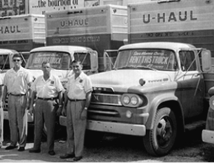 4 U-Haul employees standing in front of several U-Haul rental trucks