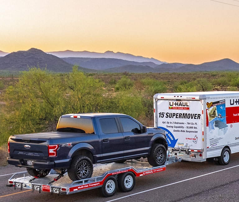 U-Haul Truck towing a trailer on a coastal road