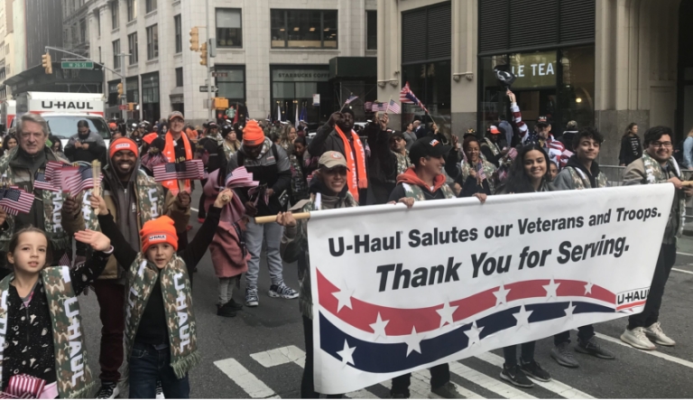 U-Haul employees marching in a parade with a banner supporting our Veterans and Troops