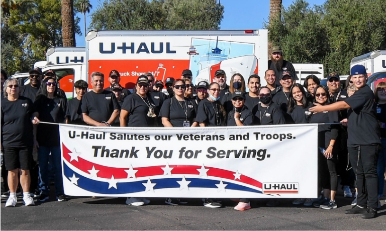 U-Haul employees displaying a banner thanking and supporting veterans and military personnel