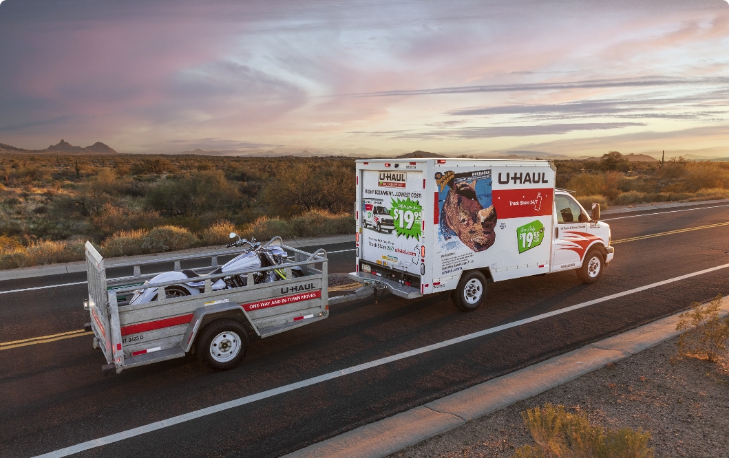 A U-Haul Truck pulling a trailer along a freeway