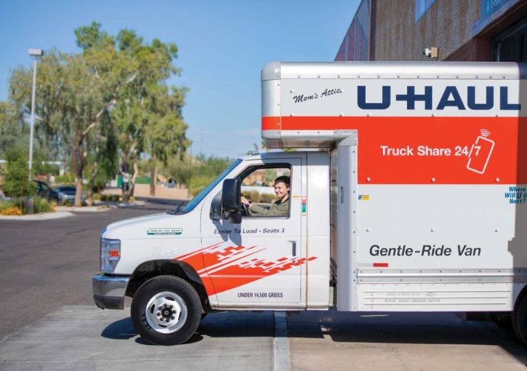 A woman driving a U-Haul truck from a U-Haul storage facility onto a road