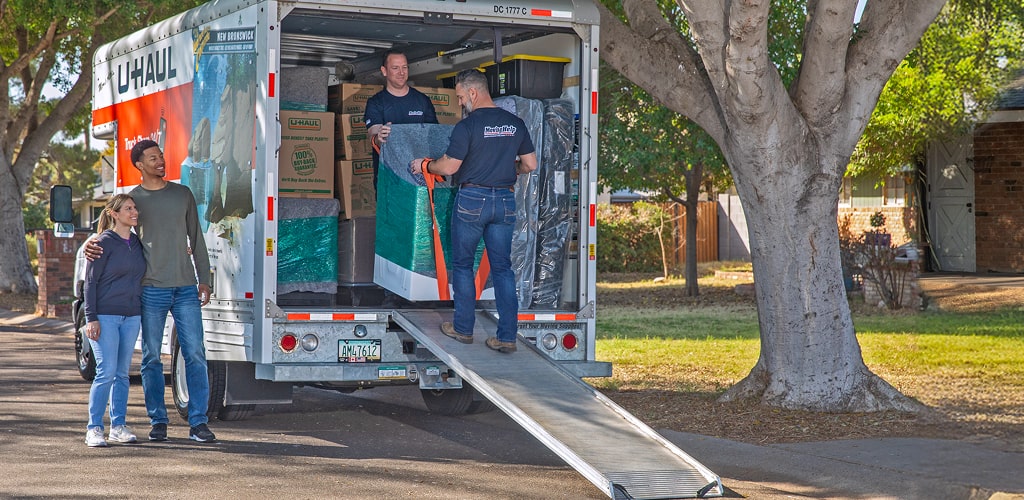 Moving Help® Service Providers unloading an washing machine from a U-Haul moving truck.