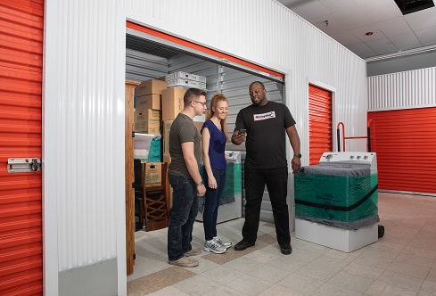 Couple standing with a moving helper in front of their climate-controlled storage unit