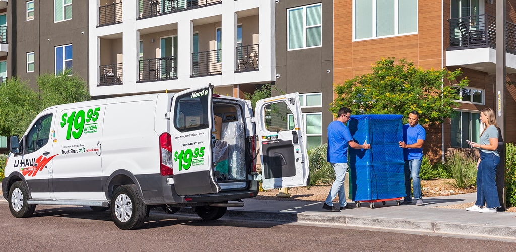 Moving Help® Service Providers unloading an armoire from a U-Haul cargovan.