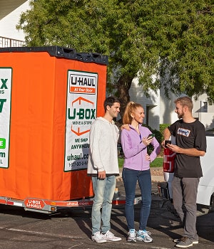 A couple chatting with a Moving Helper, providing payment code for U-Box delivery