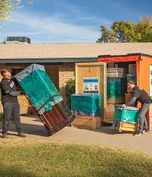 Moving Helpers unloading furniture from a U-Box container in front of a family's home