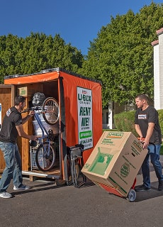 Moving Helpers loading a bicycle and boxes into a U-Box container