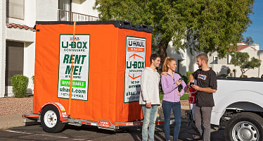 A couple chatting with a Moving Helper, providing payment code for U-Box delivery