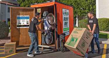 Moving Helpers loading a bicycle and boxes into a U-Box container