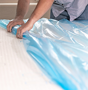 A man covering a mattress with a mattress bag
