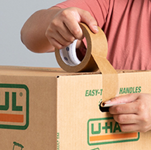 Colocar cinta de embalaje en una caja para mudanza