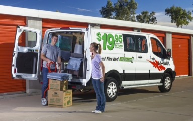 Una pareja descargando una van de alquiler de U-Haul en una instalación de almacenamiento de U-Haul