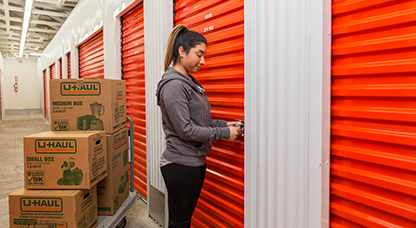 Woman with boxes opening storage unit