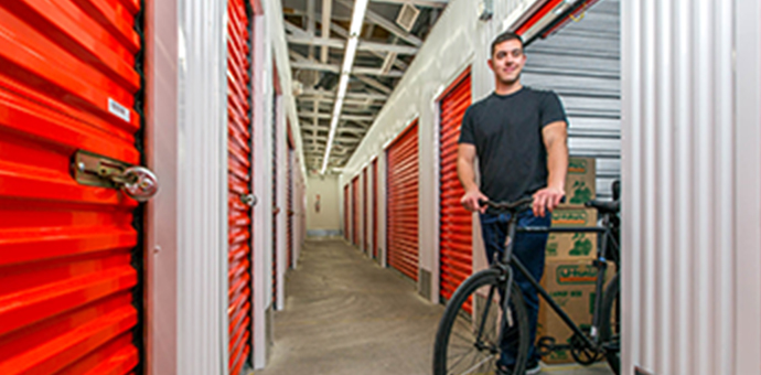 Homme avec vélo et boîtes dans une unité d'entreposage