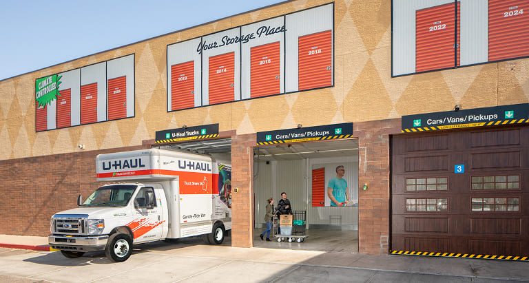 A view of the side of storage facility where a moving truck is being unloaded into a storage unit.