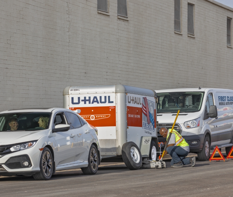 U-Haul Roadside Service Provider replacing the tire on a customer's U-Haul moving trailer.
